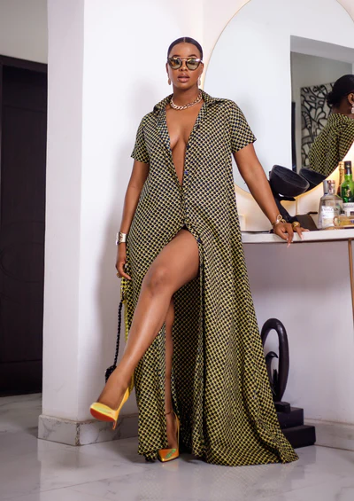 A woman posing in a short sleeve African print maxi dress shown in black and yellow.